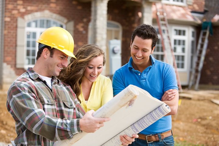 Homebuyers looking at floorplan blueprint with builder